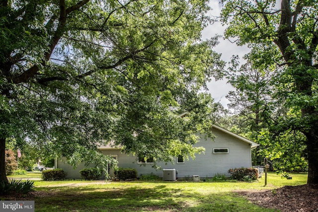 view of side of property with central AC and a yard