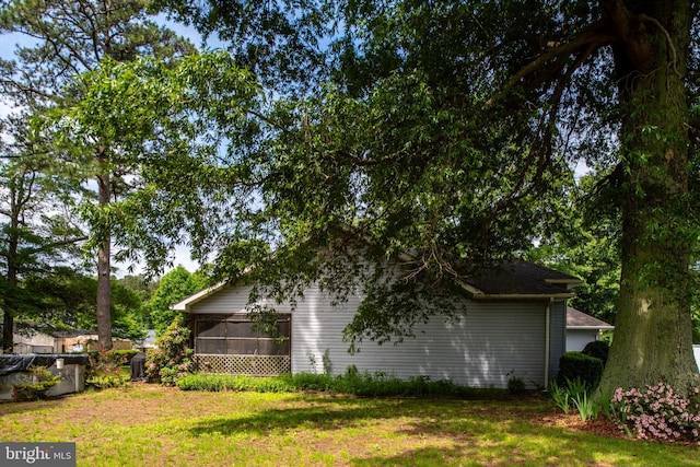 view of side of home featuring a lawn and a sunroom