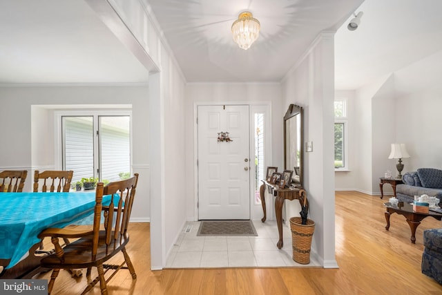 foyer featuring light hardwood / wood-style floors, ornamental molding, and a chandelier