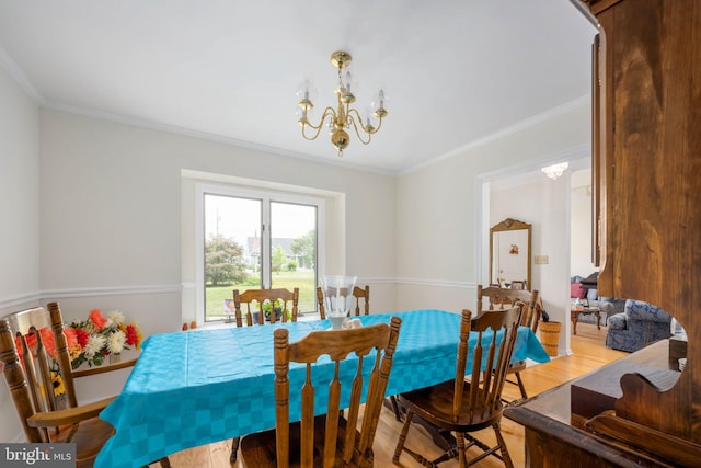 dining space with light hardwood / wood-style flooring, an inviting chandelier, and ornamental molding