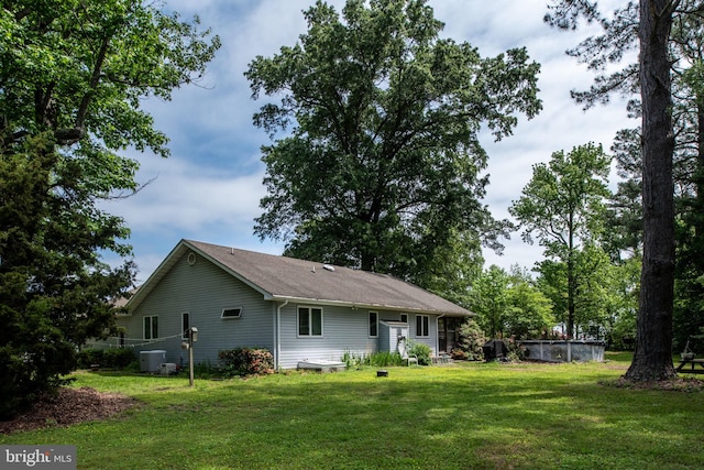 back of property with a yard and central AC