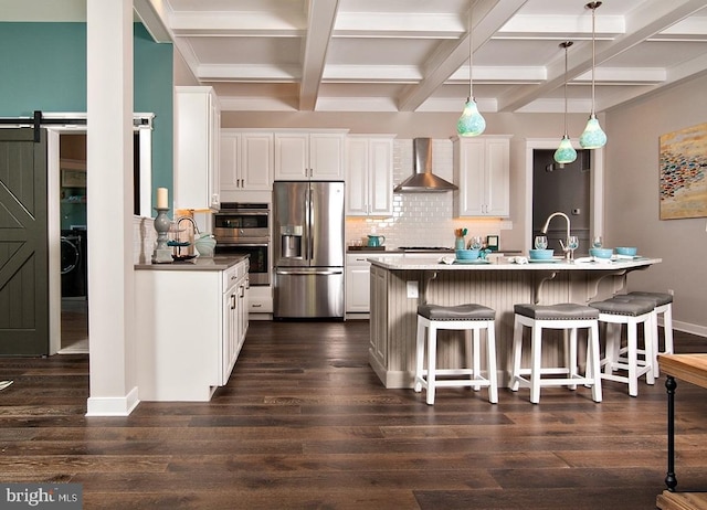 kitchen with appliances with stainless steel finishes, dark wood-type flooring, wall chimney exhaust hood, and decorative light fixtures