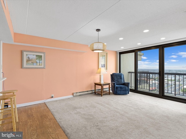 living area featuring a textured ceiling, baseboard heating, expansive windows, and hardwood / wood-style flooring