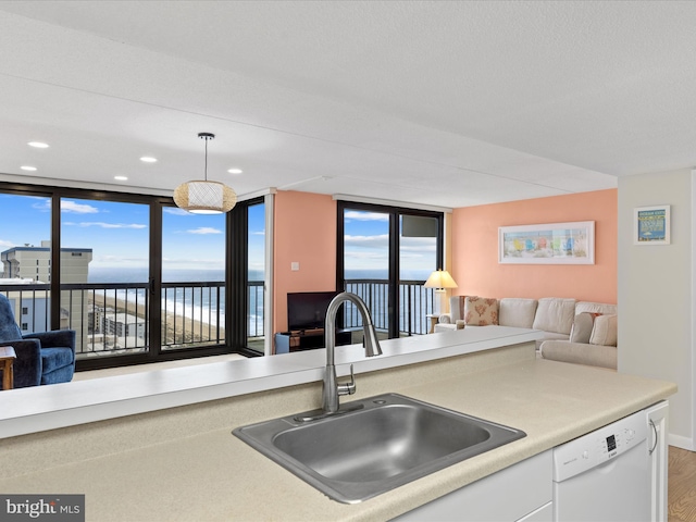 kitchen featuring white dishwasher, hanging light fixtures, sink, hardwood / wood-style flooring, and floor to ceiling windows