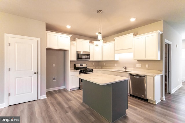 kitchen with white cabinets, appliances with stainless steel finishes, a center island, and decorative light fixtures