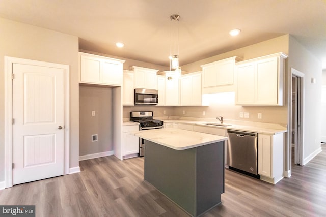 kitchen with white cabinets, a kitchen island, hanging light fixtures, and appliances with stainless steel finishes