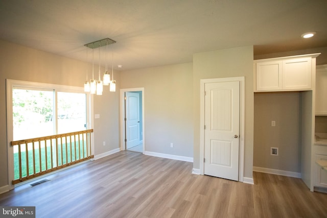 unfurnished room with light hardwood / wood-style floors and a notable chandelier