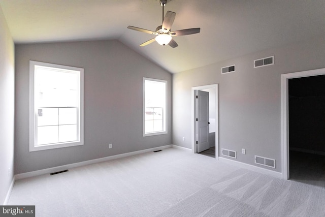 unfurnished bedroom featuring lofted ceiling, light carpet, a walk in closet, ceiling fan, and a closet