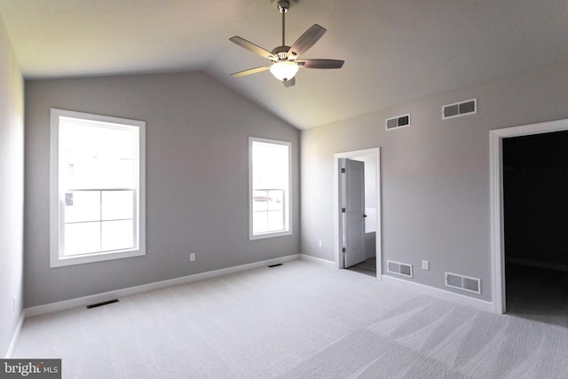 unfurnished bedroom featuring light carpet, ensuite bath, vaulted ceiling, a spacious closet, and a closet