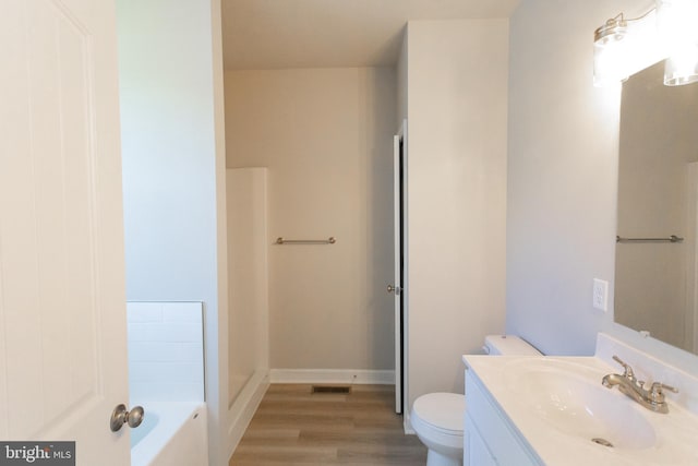 bathroom with a washtub, wood-type flooring, vanity, and toilet