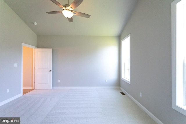 carpeted empty room with ceiling fan, a healthy amount of sunlight, and vaulted ceiling