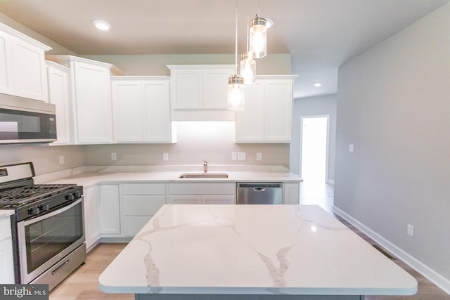 kitchen featuring white cabinets, appliances with stainless steel finishes, decorative light fixtures, and sink