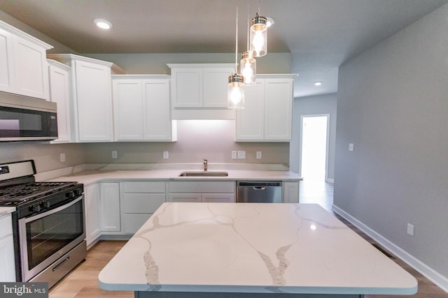 kitchen with stainless steel appliances, sink, white cabinets, light hardwood / wood-style floors, and hanging light fixtures