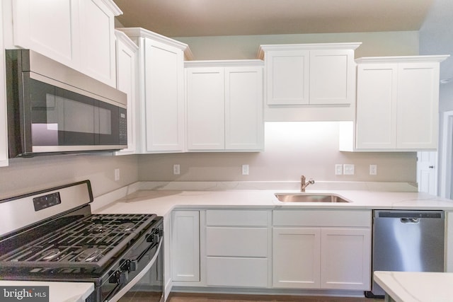 kitchen with appliances with stainless steel finishes, white cabinetry, and sink