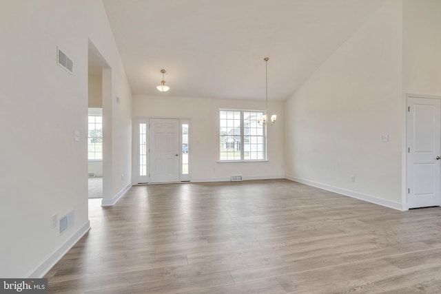 foyer entrance with high vaulted ceiling, a notable chandelier, and light wood-type flooring