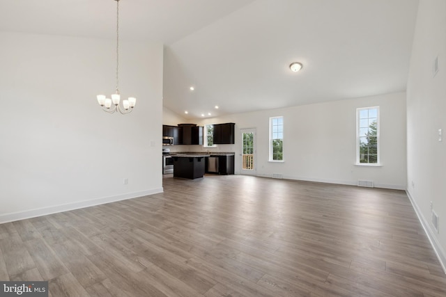 unfurnished living room with a chandelier, wood-type flooring, and high vaulted ceiling