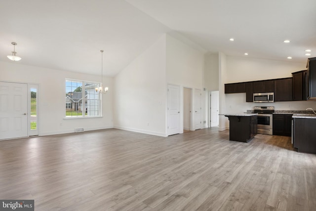 kitchen with hanging light fixtures, a kitchen island, stainless steel appliances, and light hardwood / wood-style floors