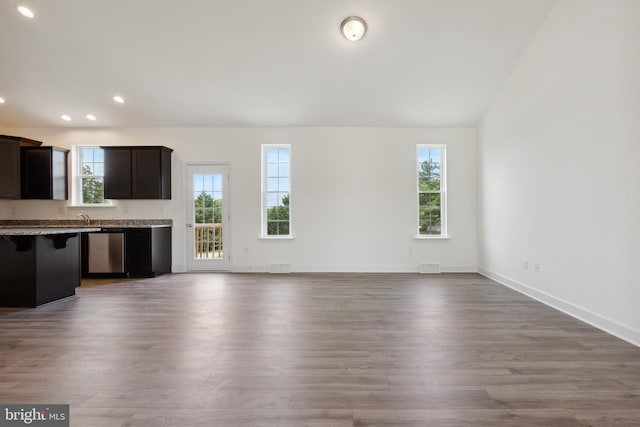 unfurnished living room featuring a wealth of natural light, hardwood / wood-style floors, and lofted ceiling