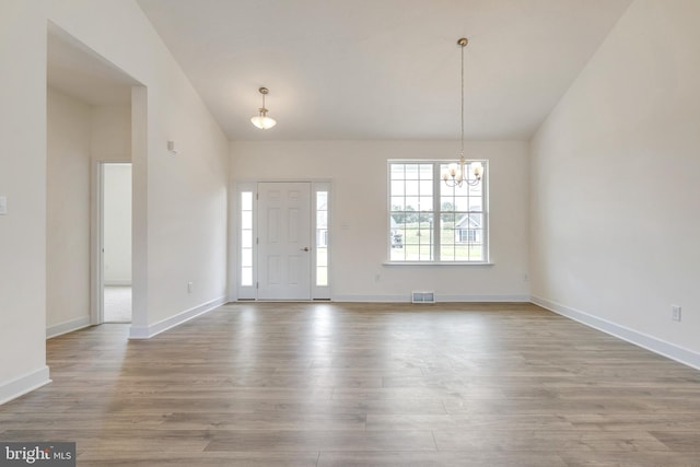 foyer with vaulted ceiling, hardwood / wood-style flooring, and an inviting chandelier