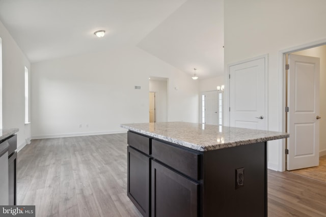 kitchen featuring a center island, lofted ceiling, light hardwood / wood-style floors, and light stone counters