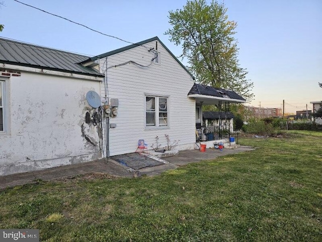 back house at dusk featuring a lawn