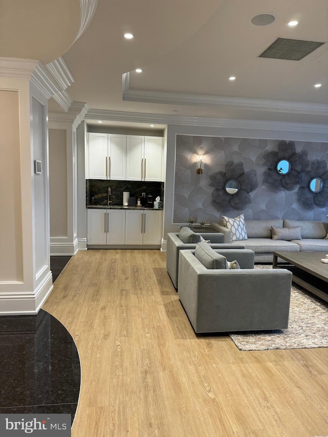 living room featuring sink, crown molding, and light wood-type flooring