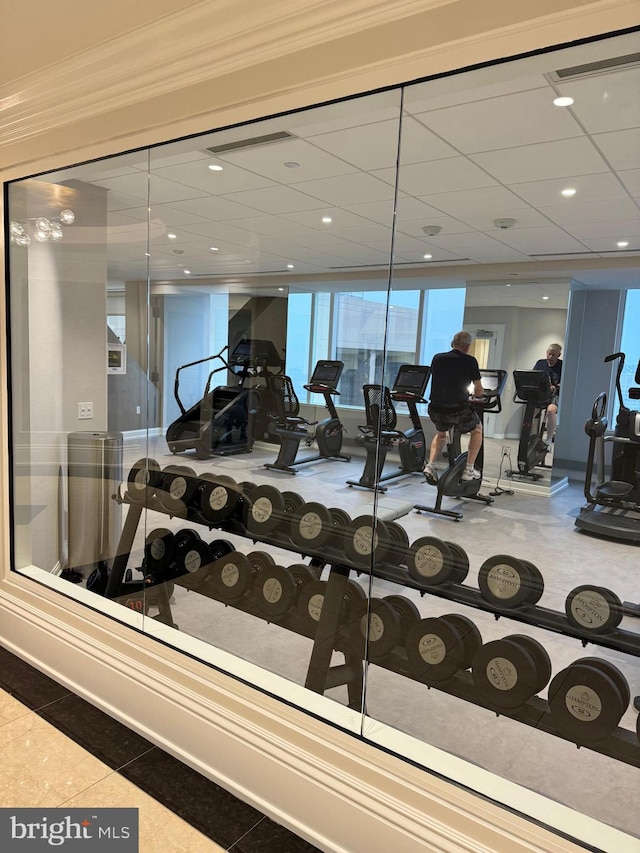 workout area featuring crown molding and tile floors