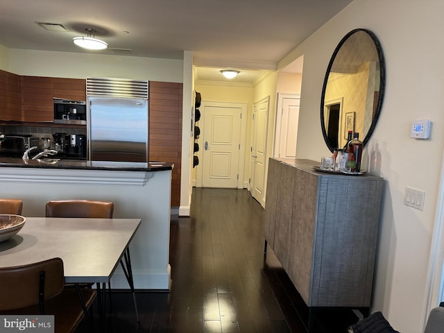 kitchen featuring sink, stainless steel built in fridge, kitchen peninsula, and dark wood-type flooring