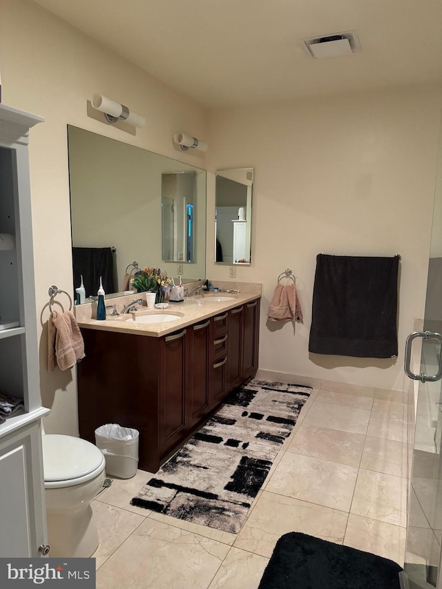 bathroom featuring a shower with door, tile floors, toilet, and double sink vanity