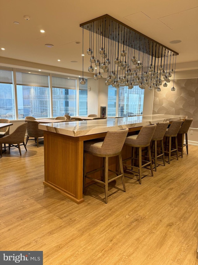 kitchen featuring hanging light fixtures, plenty of natural light, light hardwood / wood-style floors, and a kitchen bar