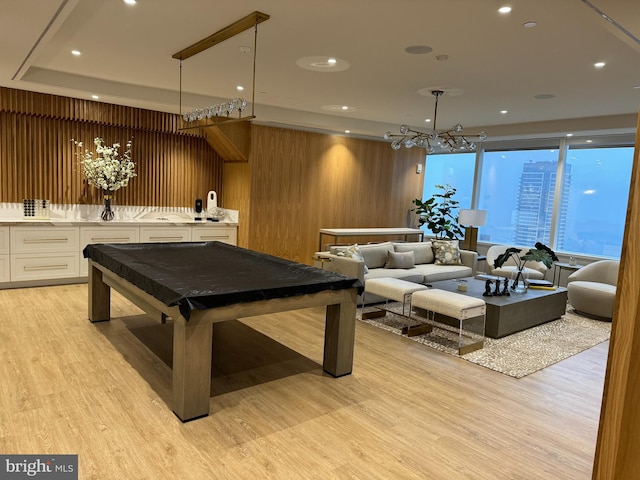 recreation room with wood walls, light hardwood / wood-style flooring, a chandelier, pool table, and floor to ceiling windows