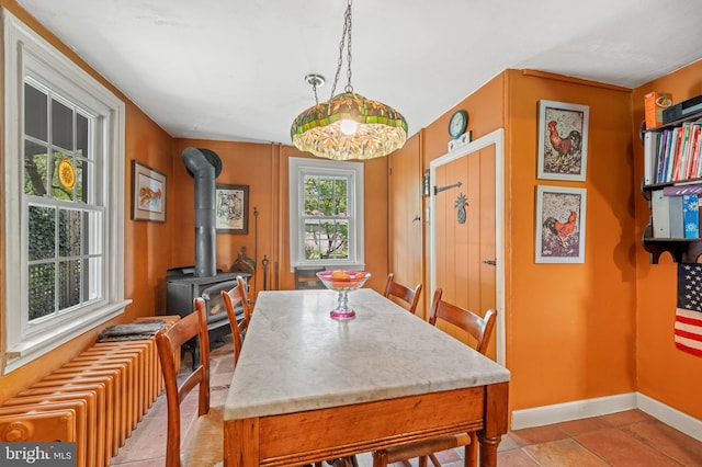 dining space featuring light tile patterned floors, a wood stove, and radiator