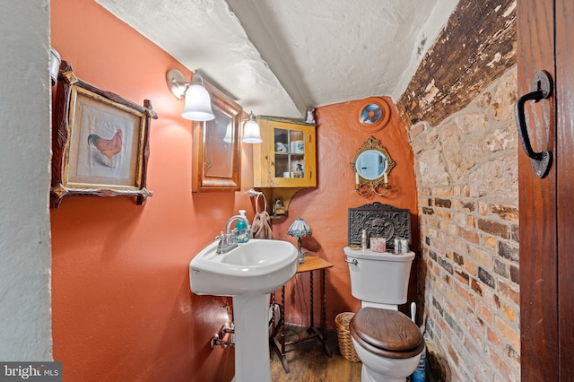 bathroom with hardwood / wood-style flooring, sink, a textured ceiling, and toilet