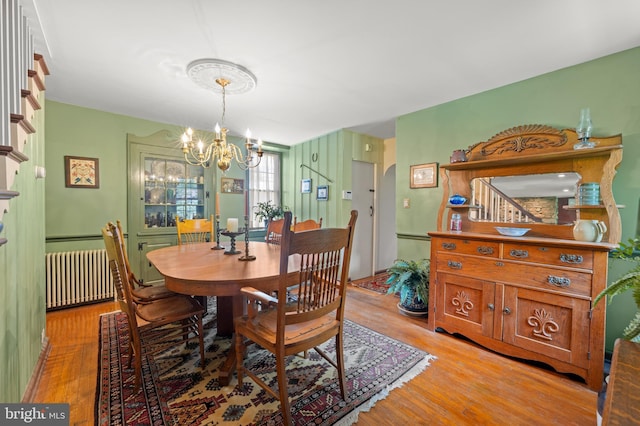 dining room with radiator, a chandelier, and light wood-type flooring