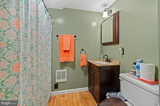 bathroom with heating unit, toilet, vanity, and hardwood / wood-style flooring