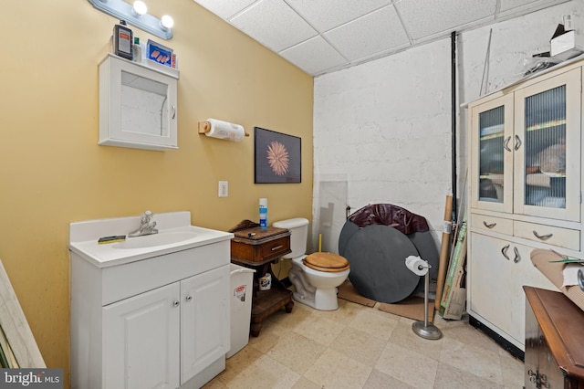 bathroom with a drop ceiling, toilet, and vanity