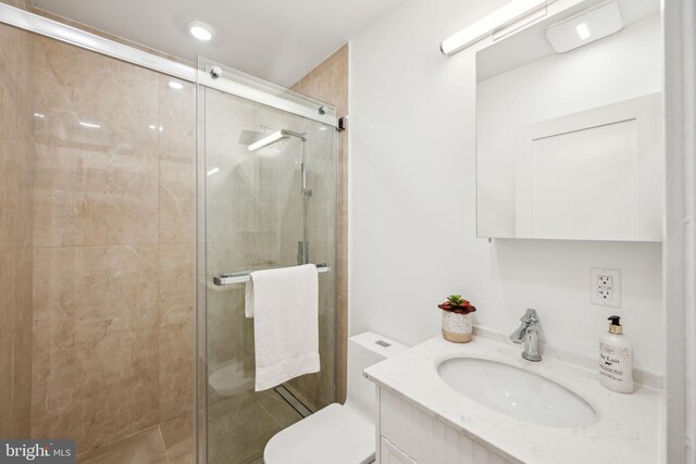 bathroom featuring vanity, toilet, and a shower with door