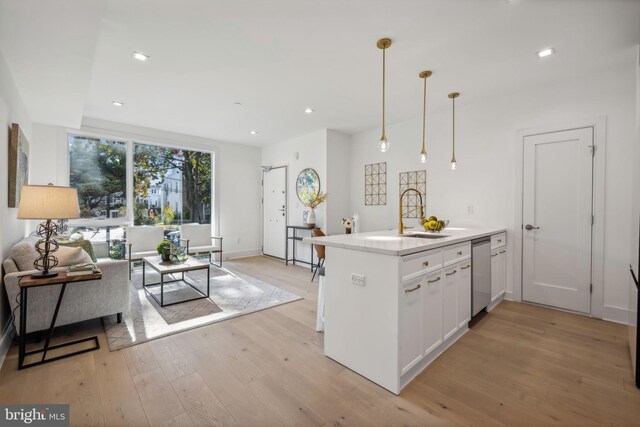 kitchen featuring white cabinetry, sink, decorative light fixtures, light wood-type flooring, and dishwasher