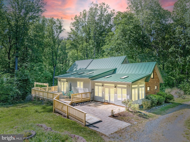 back house at dusk with a lawn and a deck