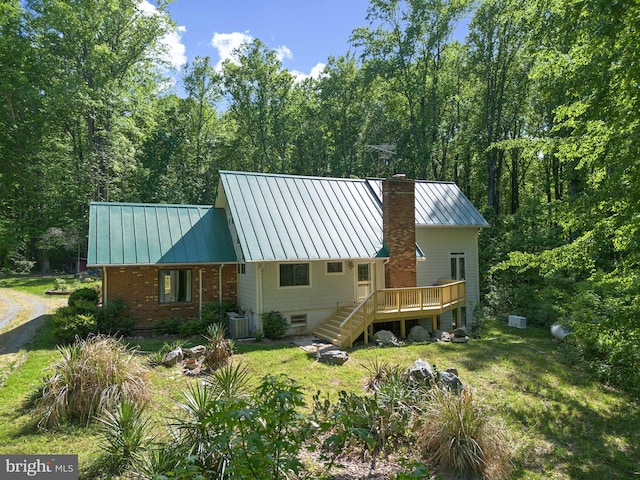 rear view of house featuring central AC unit, a yard, and a deck