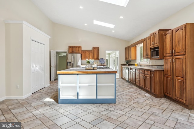 kitchen with lofted ceiling with skylight, appliances with stainless steel finishes, and a center island