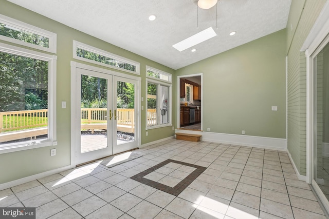 doorway with a textured ceiling, french doors, vaulted ceiling with skylight, and light tile patterned flooring