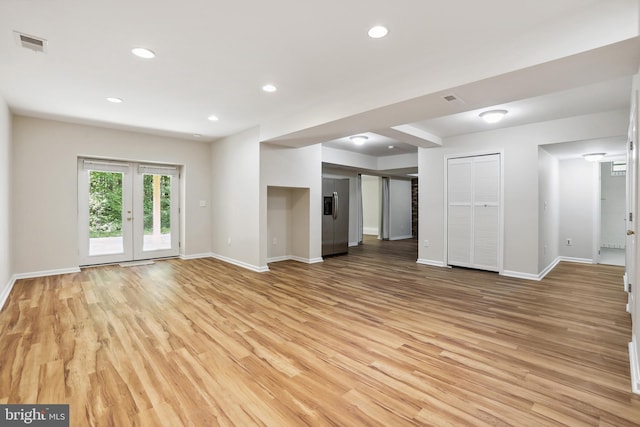 unfurnished living room featuring light wood-type flooring and french doors