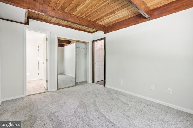 unfurnished bedroom with connected bathroom, carpet floors, wood ceiling, beam ceiling, and a closet