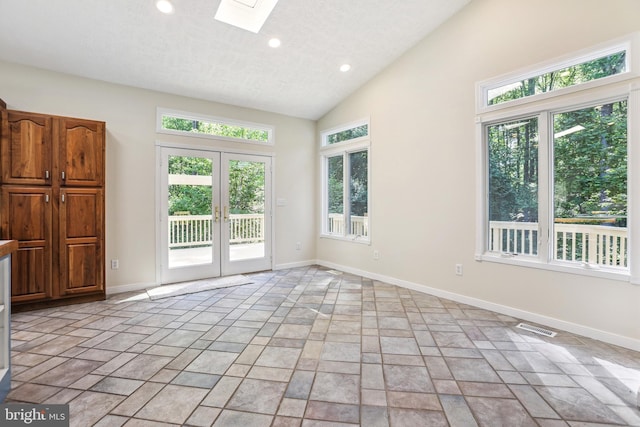 unfurnished room with vaulted ceiling with skylight and french doors