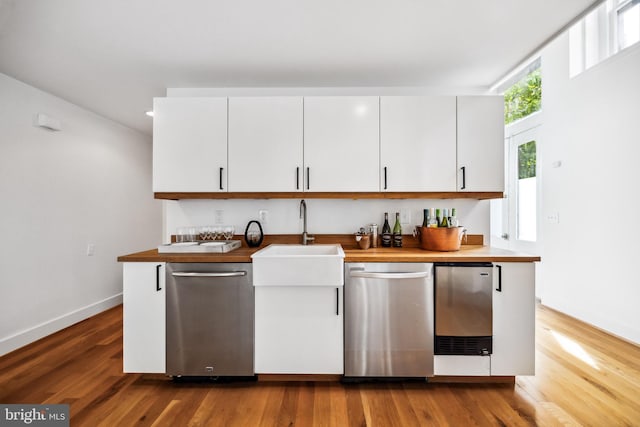 kitchen featuring stainless steel dishwasher, wood-type flooring, and white cabinetry