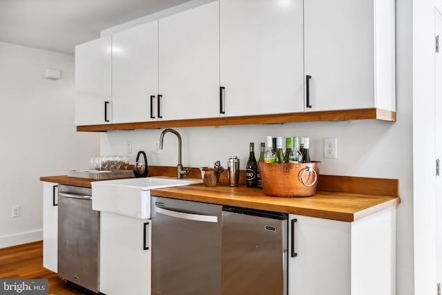 kitchen featuring wood-type flooring, butcher block countertops, sink, and dishwasher