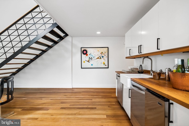 kitchen with white cabinetry, sink, light hardwood / wood-style floors, dishwasher, and butcher block counters