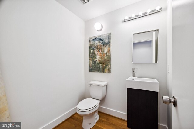 bathroom with wood-type flooring, vanity, and toilet