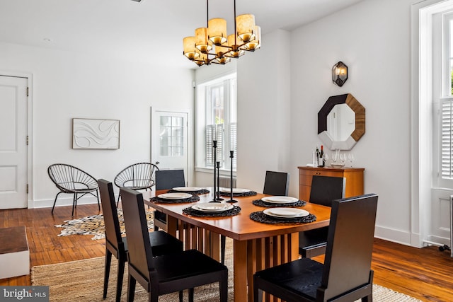 dining space featuring hardwood / wood-style flooring and an inviting chandelier